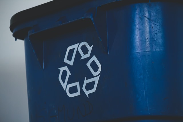 A blue bin with a recycling sign on it. 